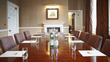 A conference room with a long table, chairs, and a fireplace.