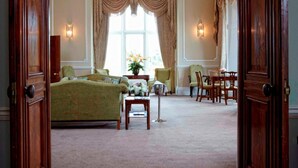A room with a large bed, a chandelier, and a window with curtains. - Wivenhoe House Hotel (Colchester)