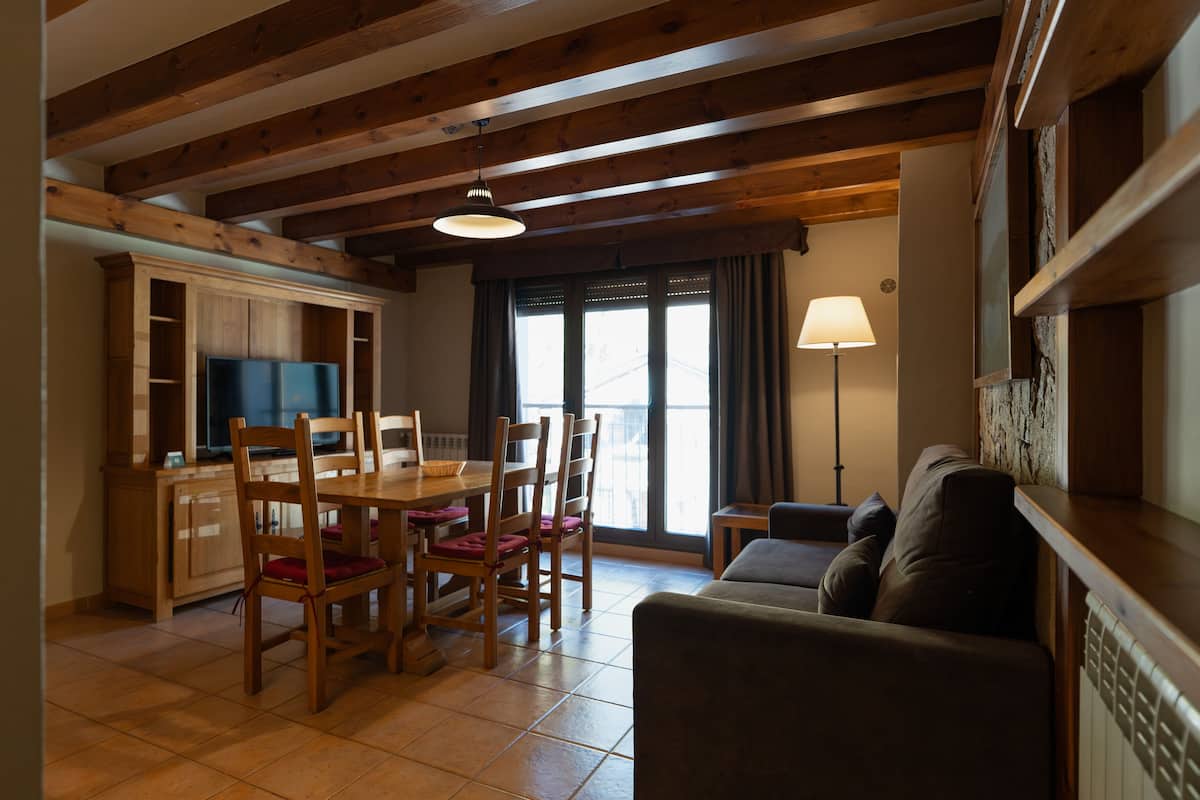 A dining area with wooden furniture, a television, and a sofa.