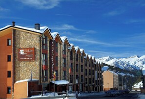 A row of stone and wood buildings with a sign for 'Els Lacs Apartments & Resorts'.