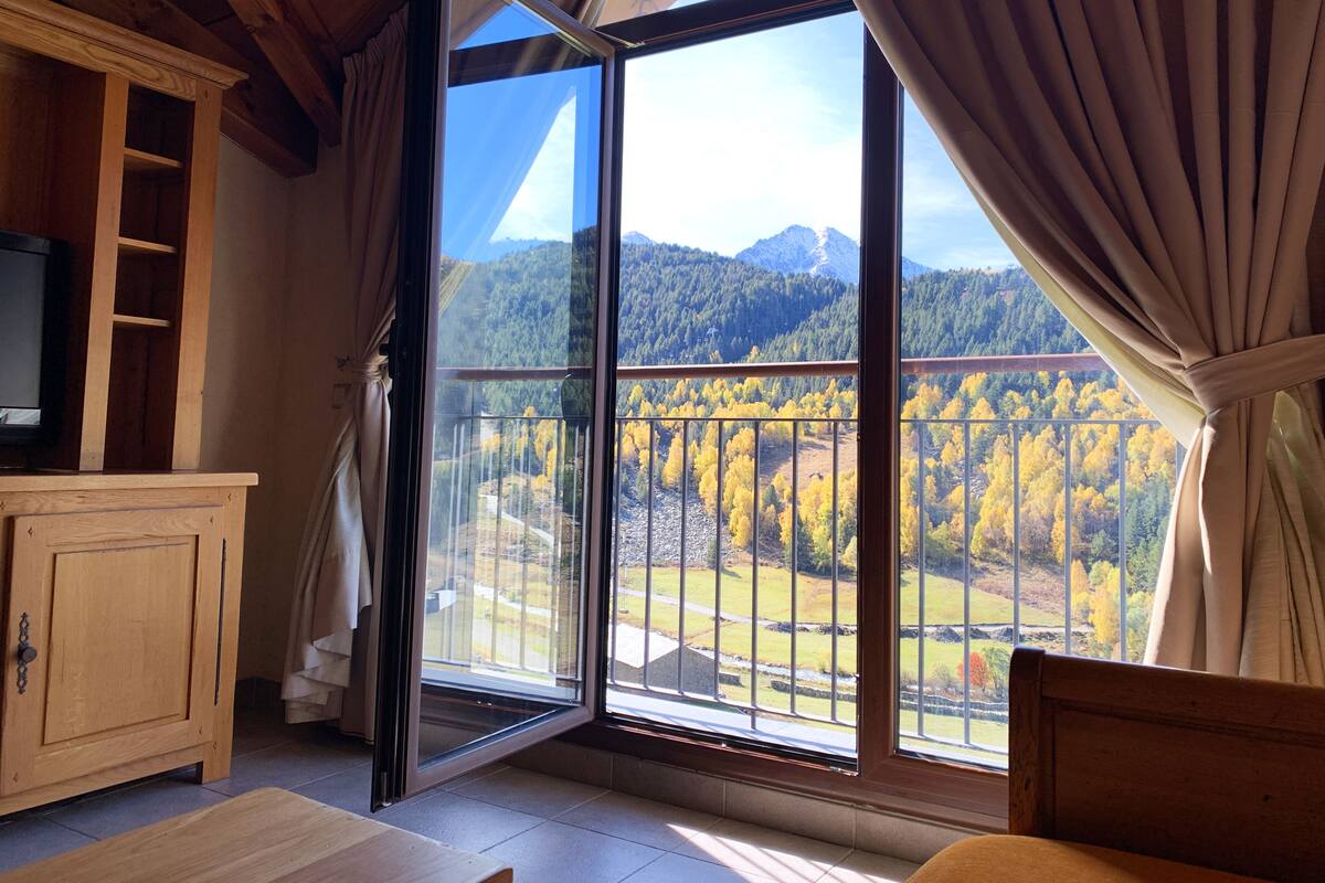 A room with a large sliding glass door leading to a balcony with a mountain view.
