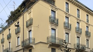 A multi-story building with balconies, arched doorways, and a sign indicating the name "Monforie." - Brera Apartments in San Babila (Milan)