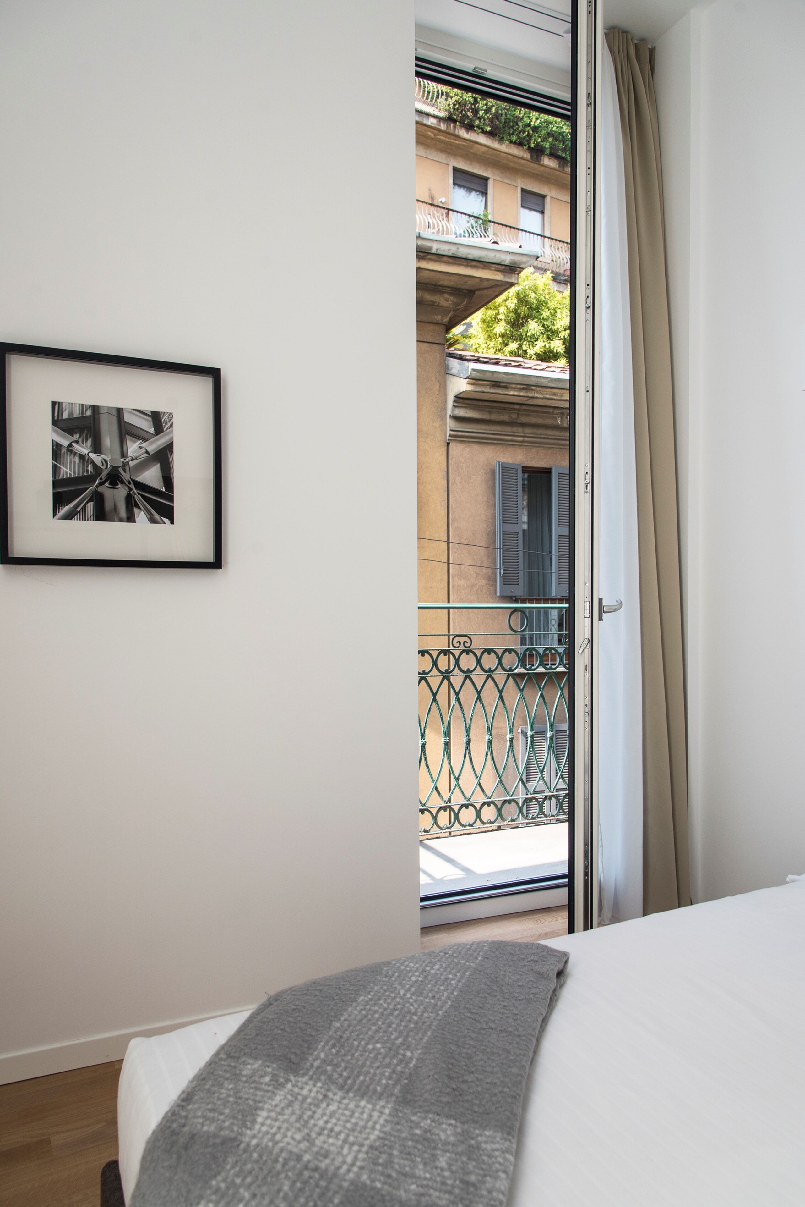 Une chambre à coucher avec un lit, un tableau encadré au mur et une vue sur un balcon extérieur.