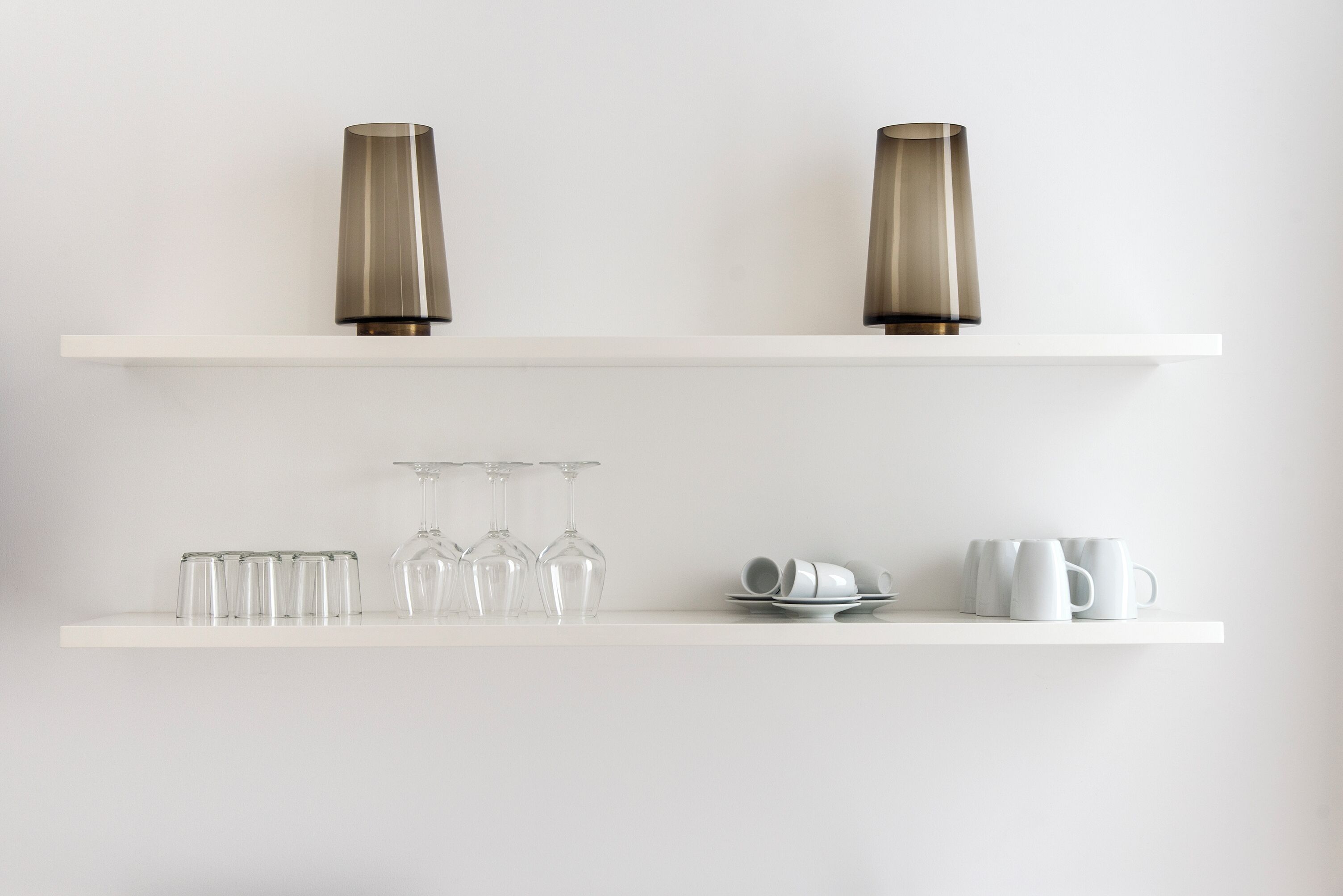 Two white shelves with decorative vases and glassware.