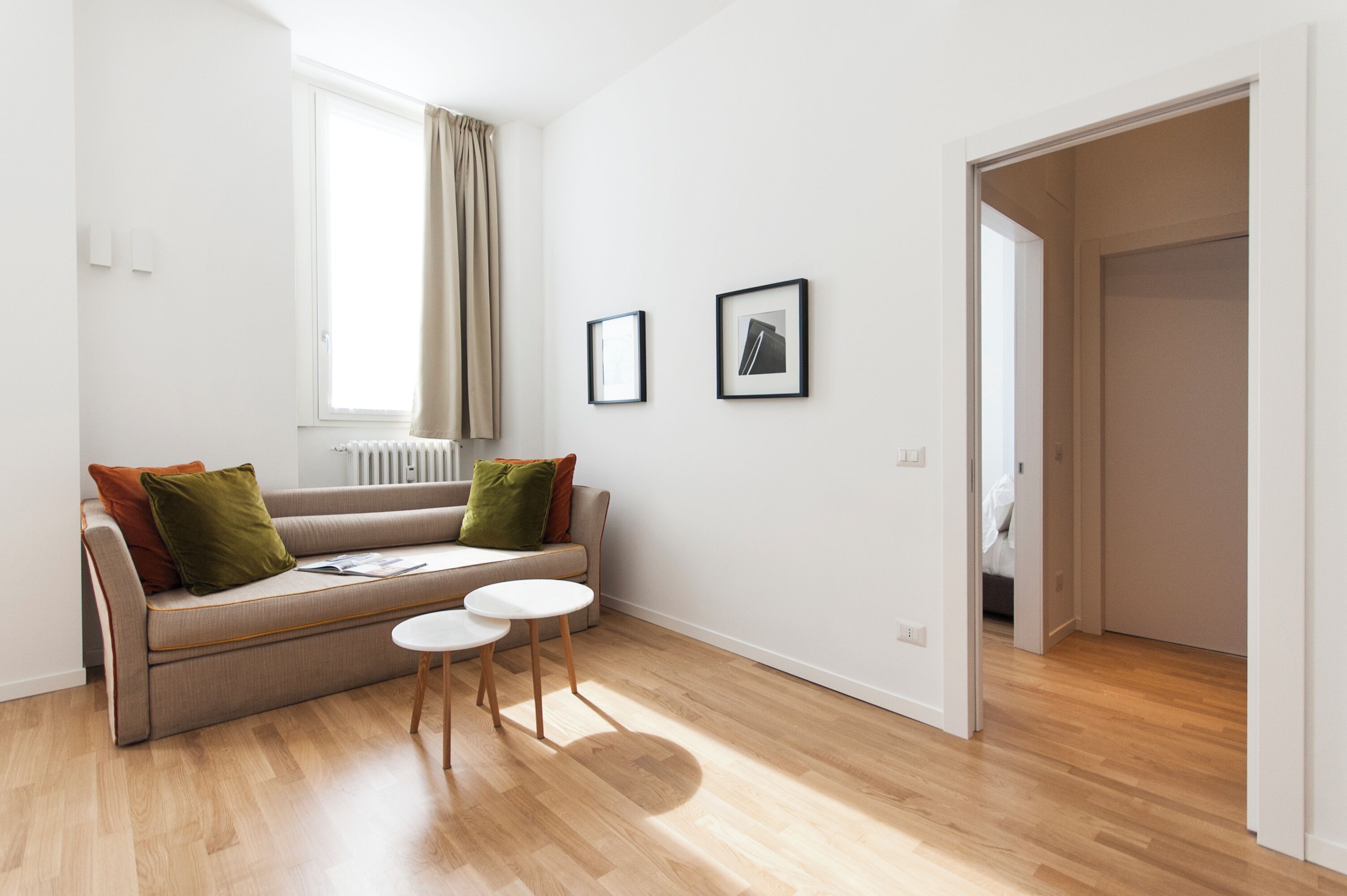 A modern living room with a sofa, two chairs, a radiator, and framed pictures on the wall.