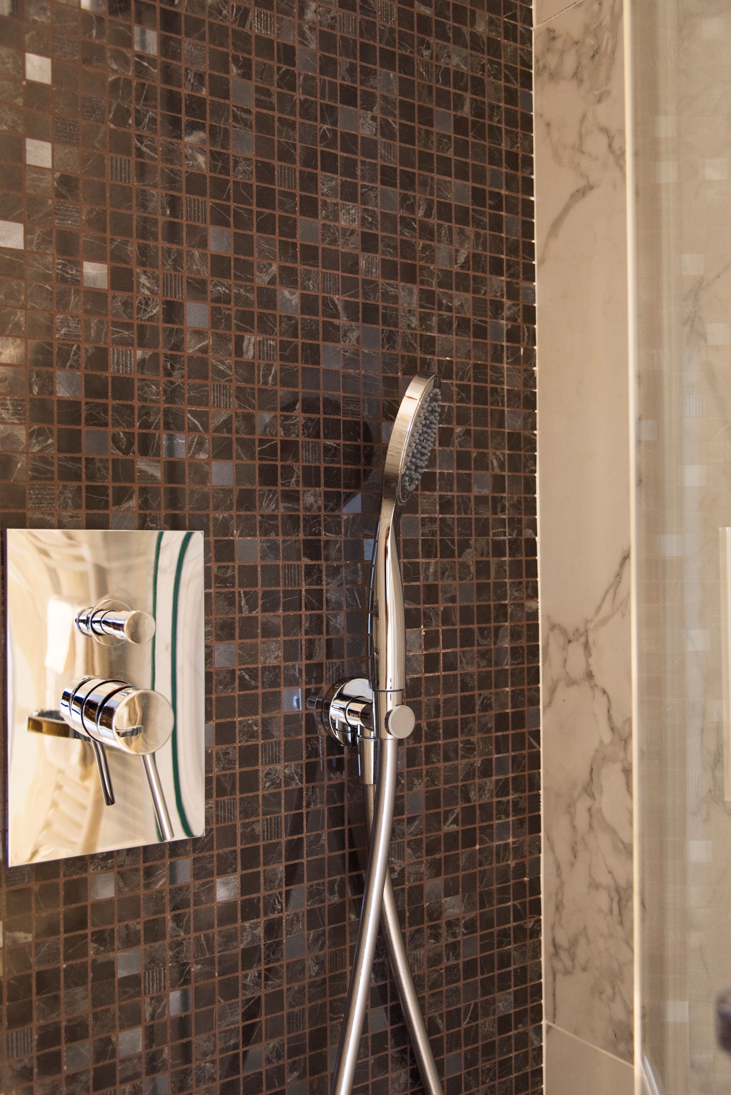 Une salle de bain avec une douche, un miroir et un mur carrelé.