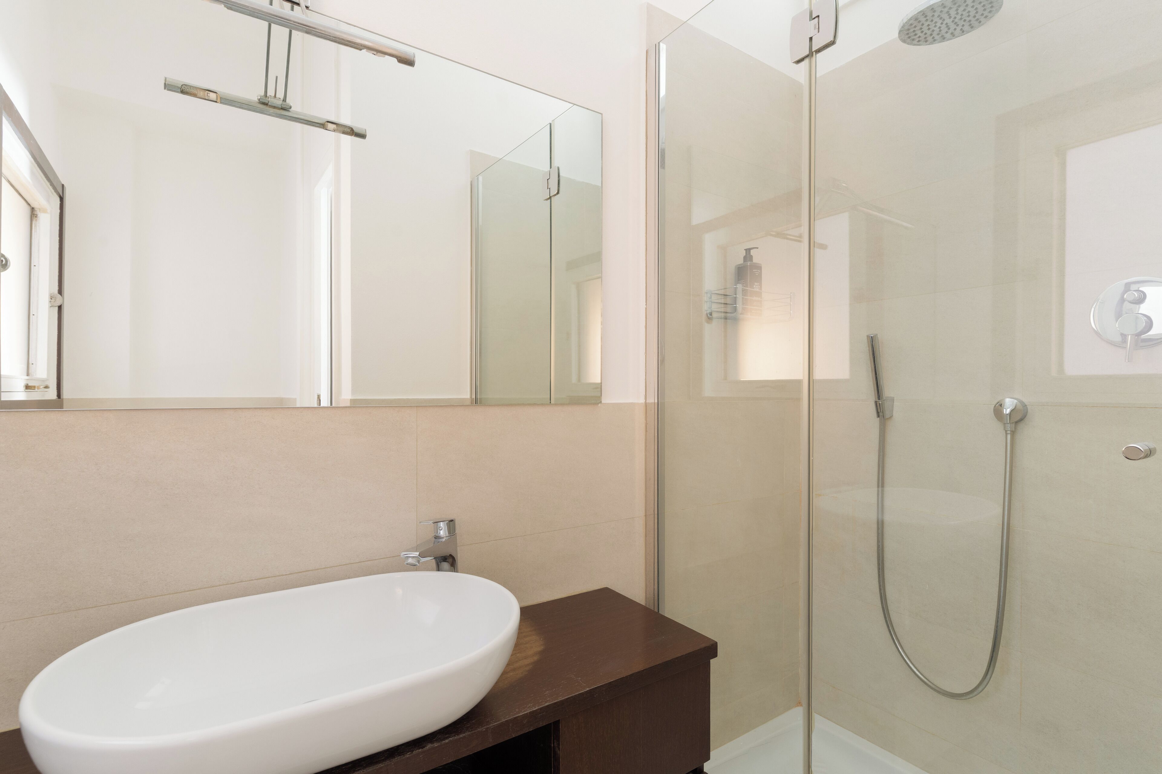 A modern bathroom with a glass-enclosed shower, a white sink, and a large mirror.