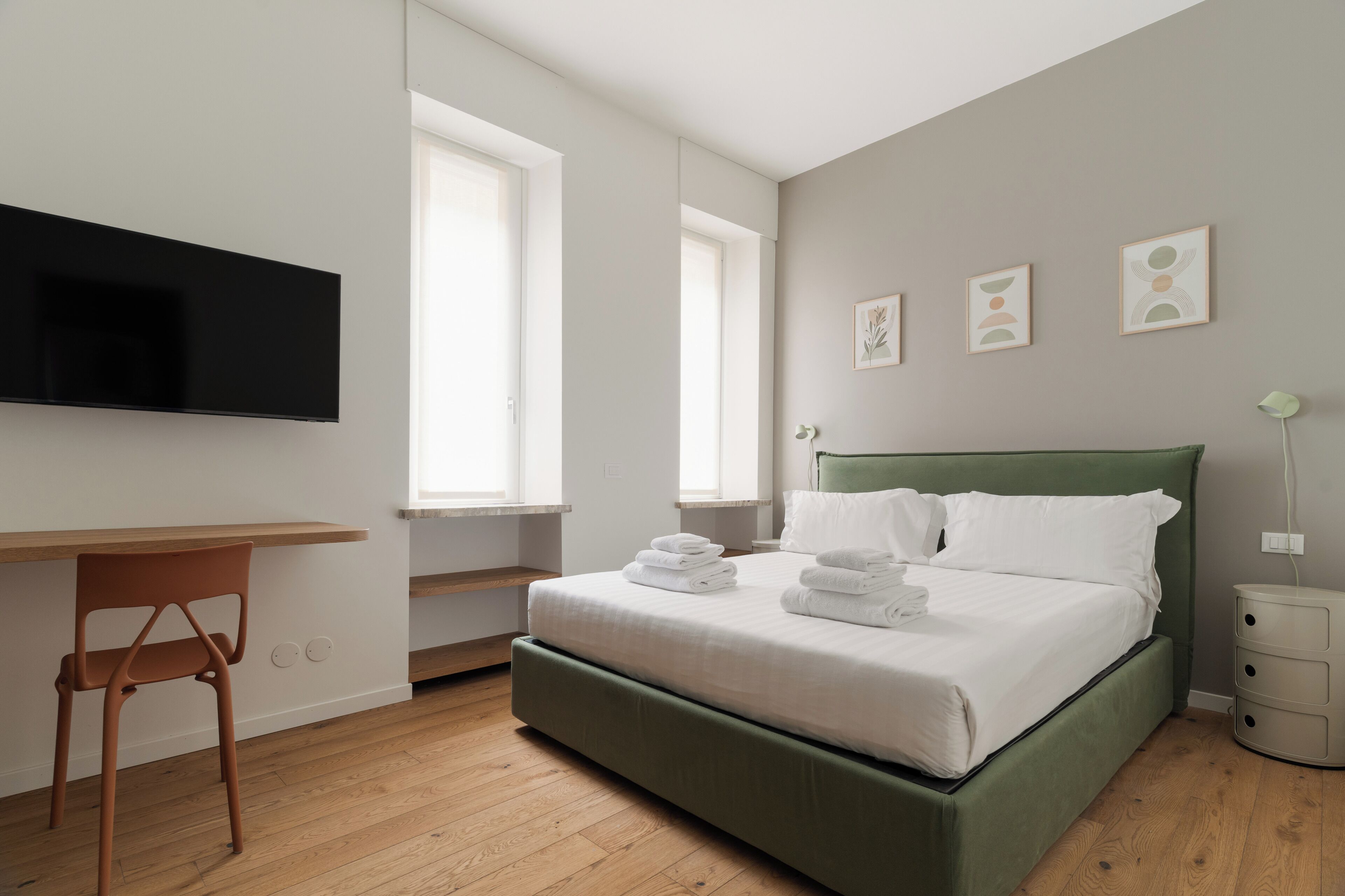 Ein Schlafzimmer mit einem Bett, einem Schreibtisch und einem an der Wand befestigten Fernseher.