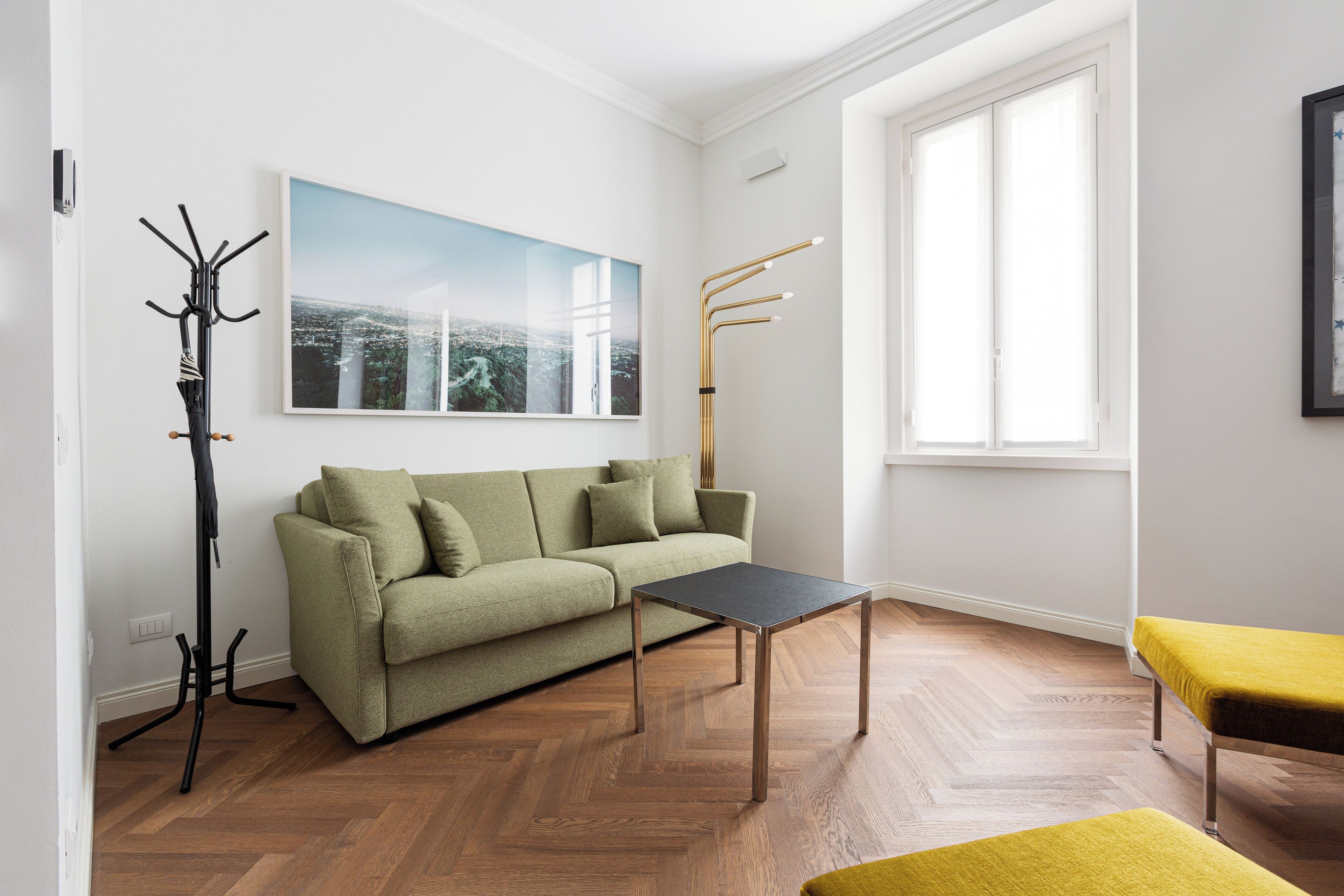 Un salon moderne avec un canapé vert, une table basse noire et un banc jaune.