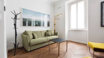 Un salon moderne avec un canapé vert, une table basse noire et un banc jaune.