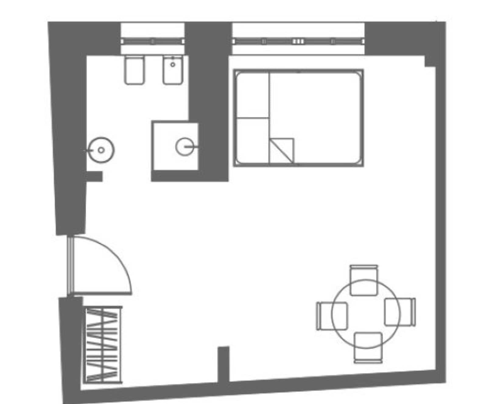 A floor plan of a hotel room with a bed, a bathroom, a small kitchen area, and a dining table.