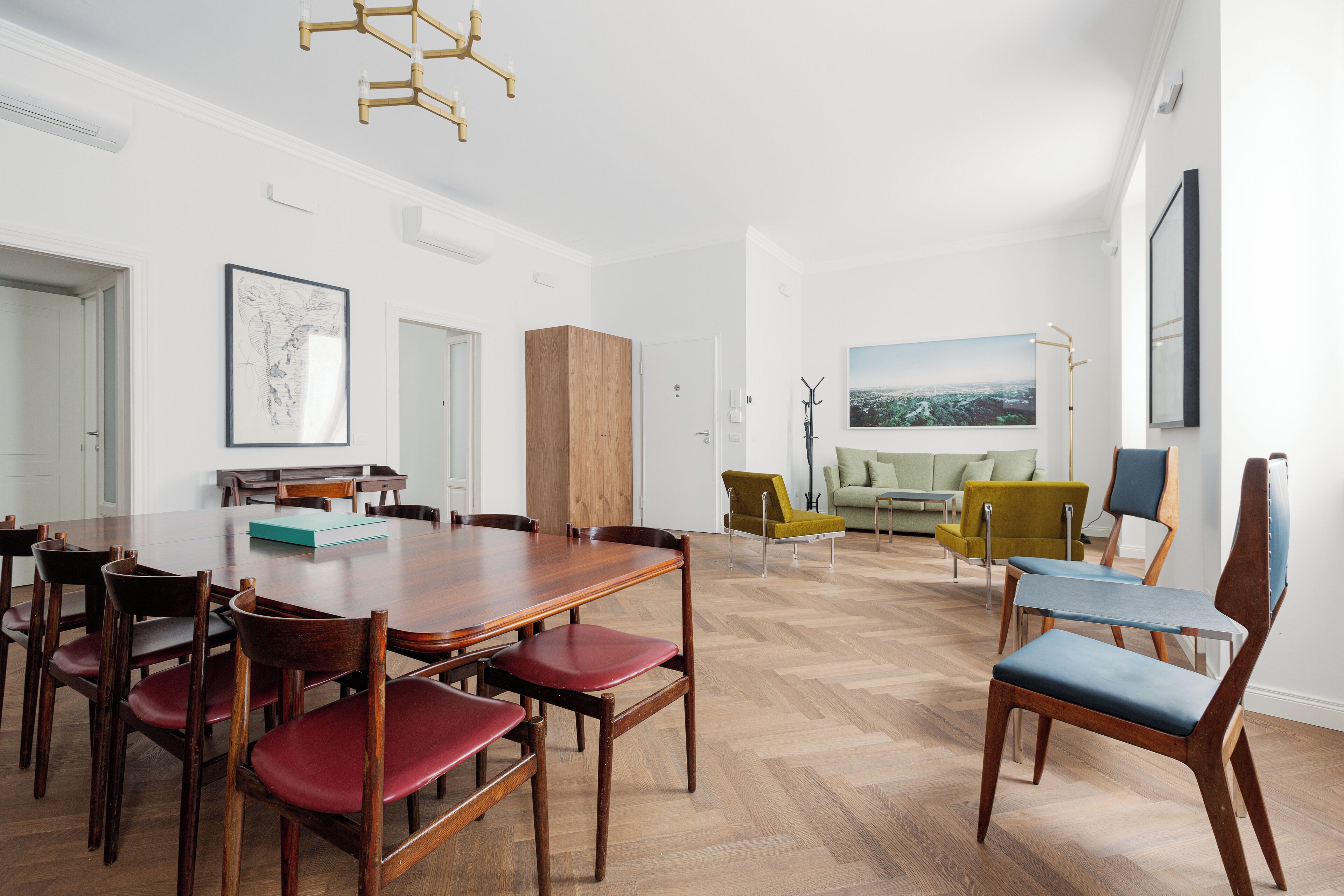 Ein geräumiges Wohnzimmer mit einem Holzesstisch und Stühlen, einem Sofa und einem großen Gemälde an der Wand.