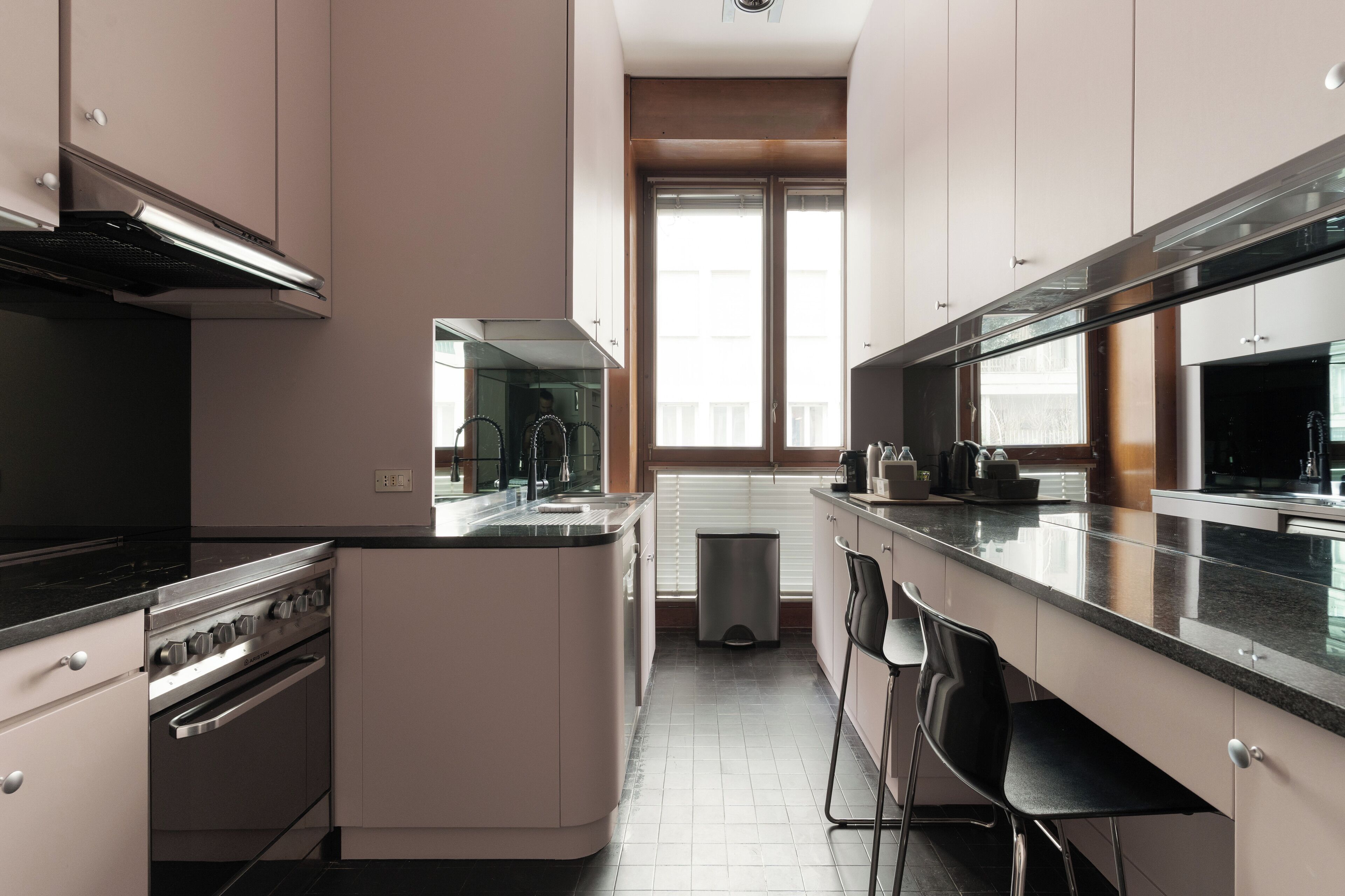 A modern kitchen with a central island, stainless steel appliances, and a large window providing natural light.