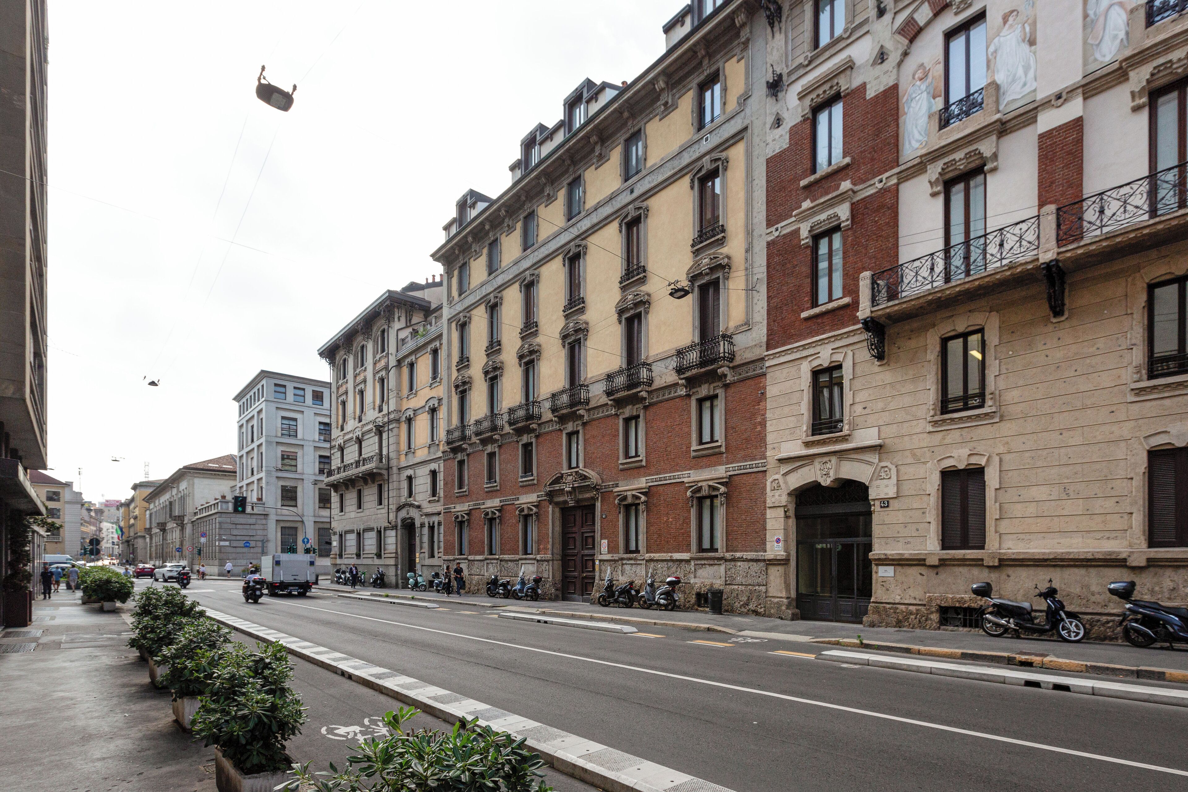 A street with buildings, a sidewalk, and parked motorcycles.