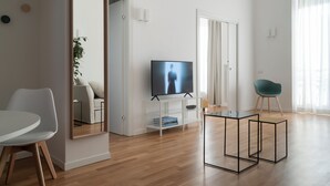 A modern living room with a flat-screen TV, a dining table, and a seating area. - Brera Apartments in San Babila (Milan)