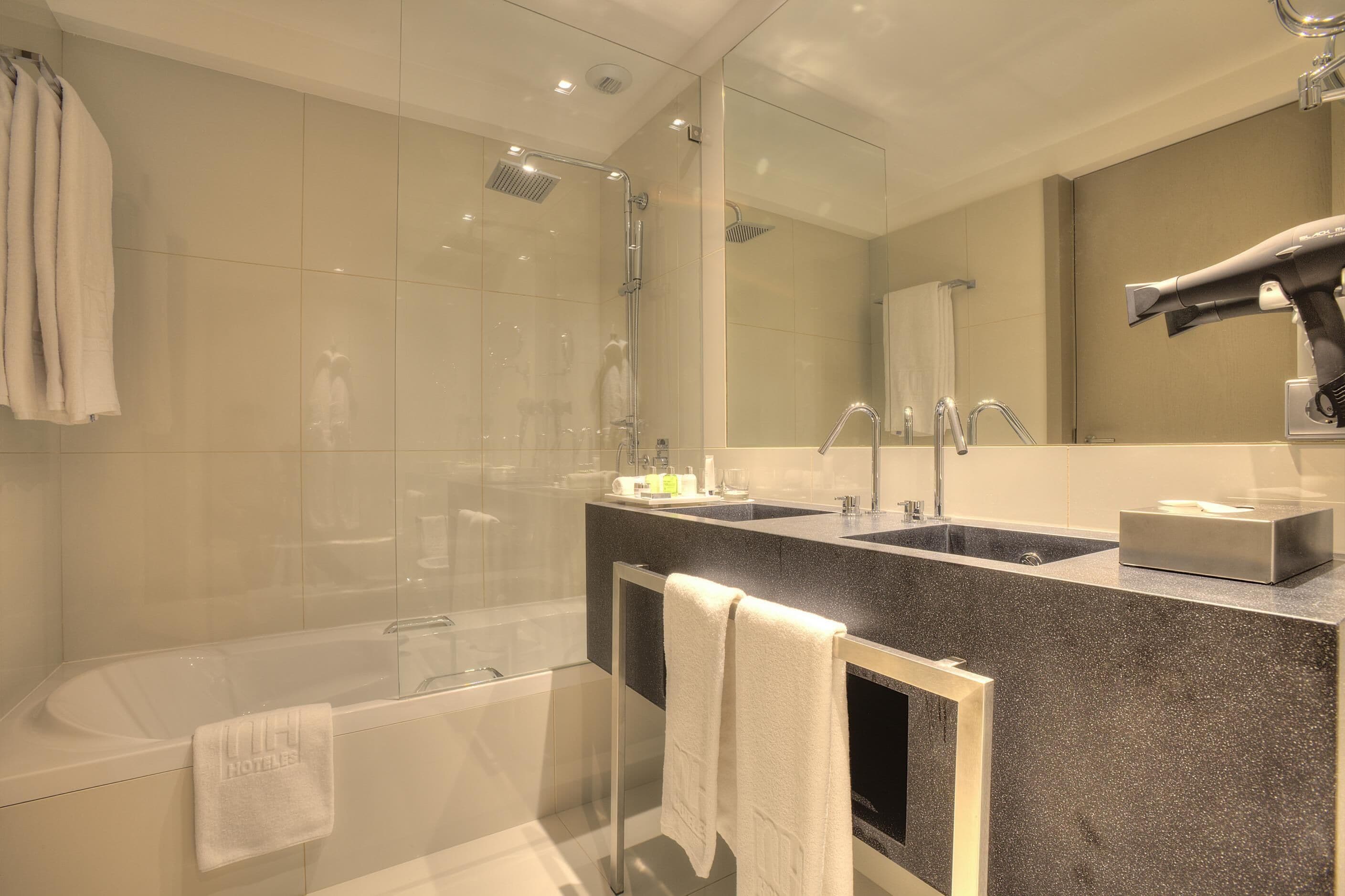Une salle de bain moderne équipée d’une baignoire, d’une douche, d’un lavabo et d’un grand miroir.