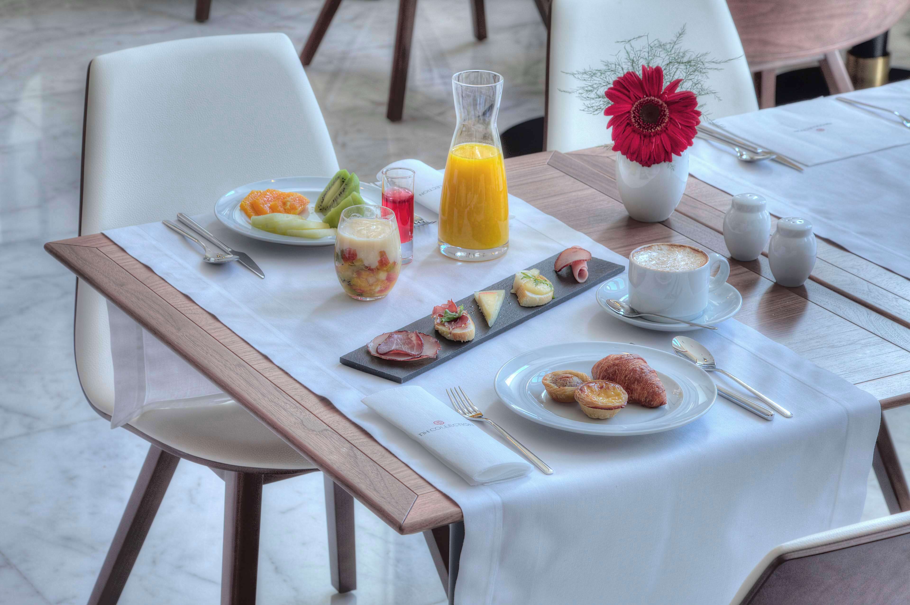 A breakfast table with a variety of food items, including fruits, pastries, and a coffee cup.