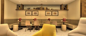 Un espacio lounge moderno con un sofá, sillas, una mesita y una estantería con cuadros enmarcados.