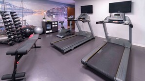 Een sportschool met loopbanden, gewichten en fitnessballen.
