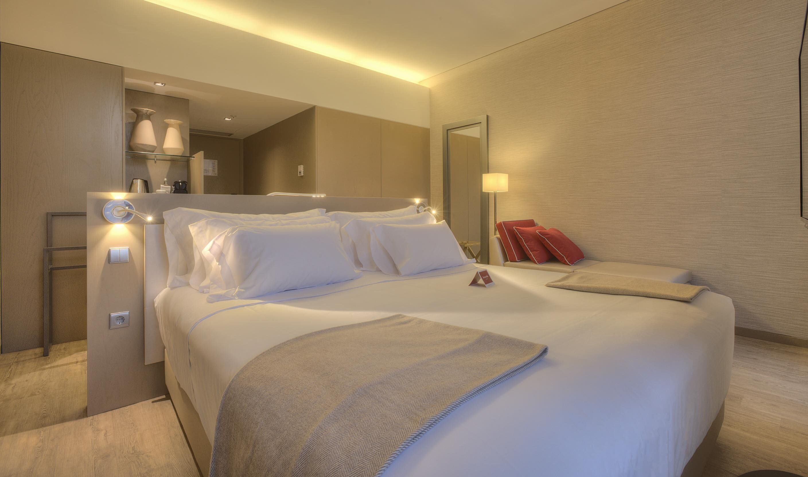 Een moderne hotelkamer met een groot bed, bedlampen en een spiegel.