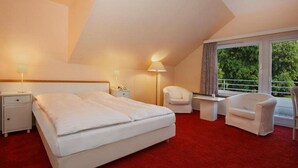 A hotel room with a large bed, two bedside tables, a chair, and a window with a view of trees. - Kaiserhof TWO by Centro Basic (Luebeck)