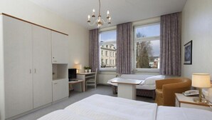 A hotel room with a bed, a desk, a chair, a TV, and a window with curtains. - Kaiserhof TWO by Centro Basic (Luebeck)