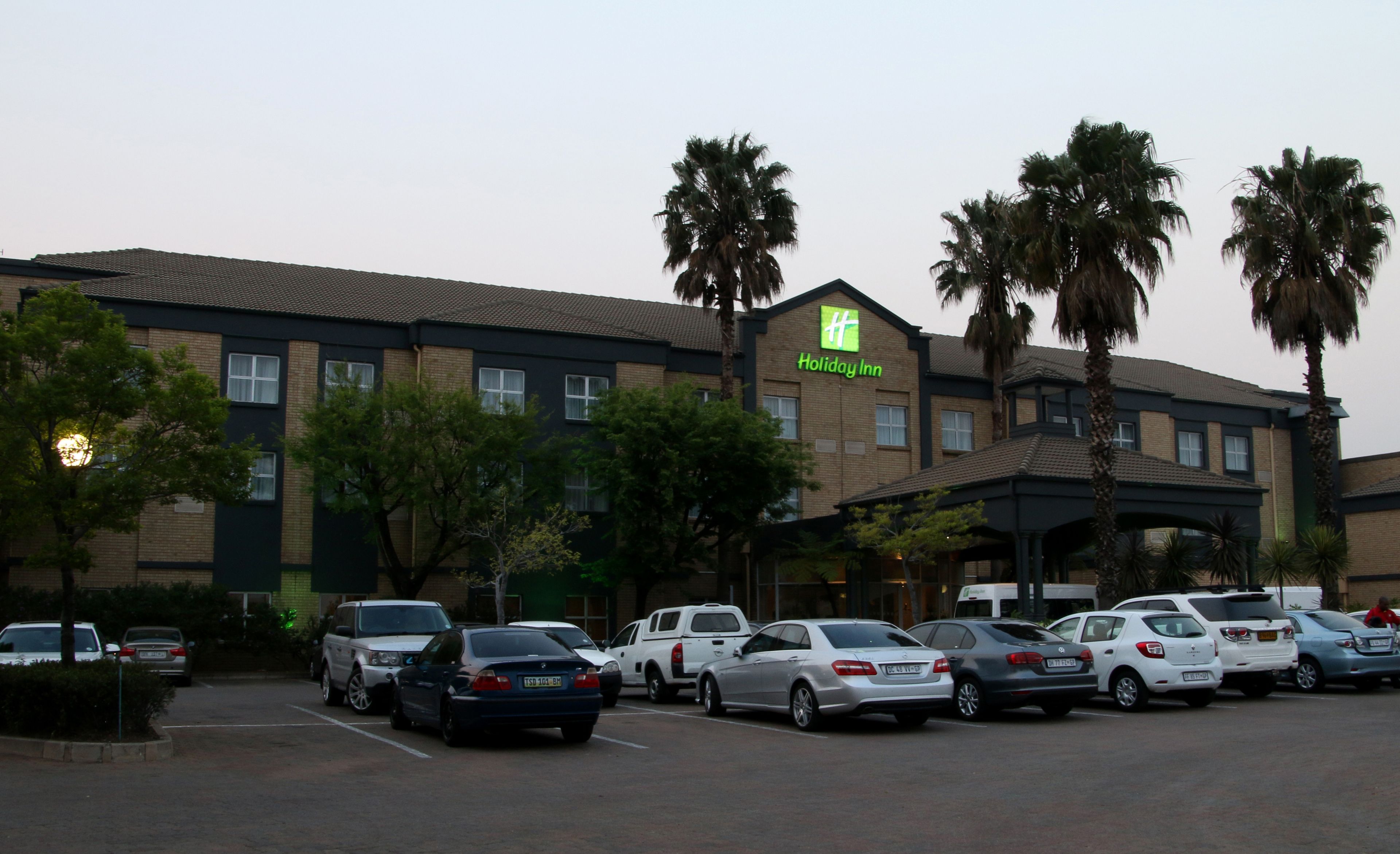 A Holiday Inn hotel with a parking lot filled with cars.
