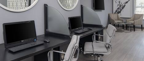 A modern office space with two desks, two chairs, a large mirror, and a flat-screen TV.