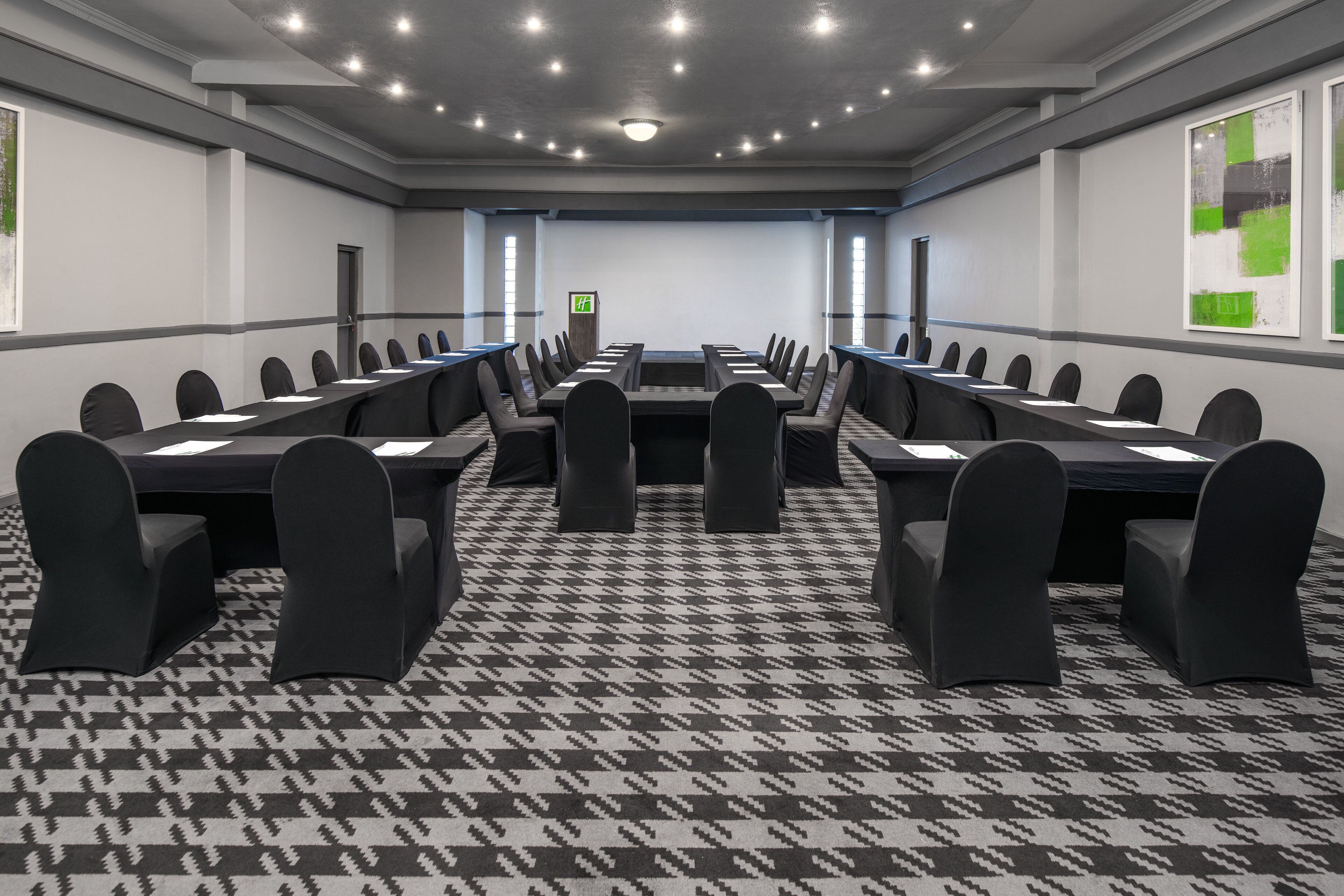 A conference room with a long table, black chairs, and a patterned carpet.