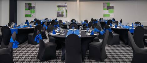 A conference room with round tables, black chairs, and blue sashes.