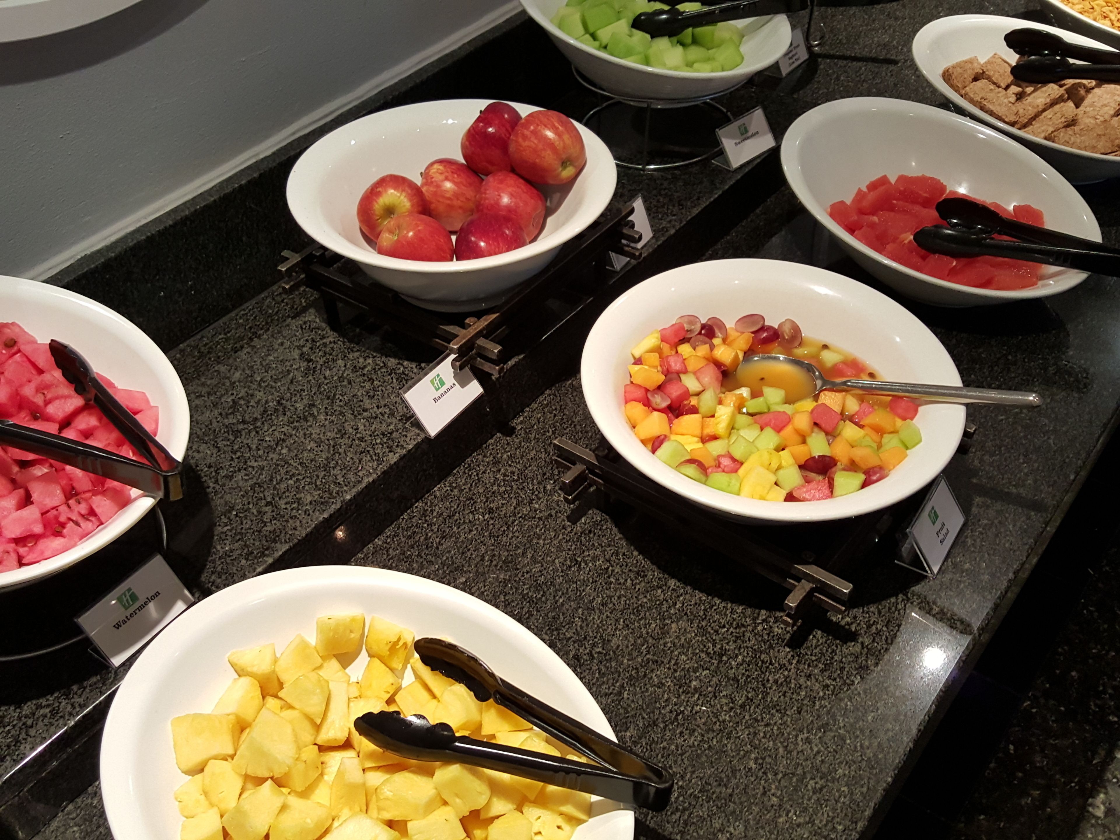 Un buffet proposant une variété de fruits, notamment des pommes, des pastèques et des ananas.