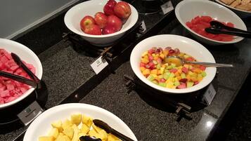Un buffet proposant une variété de fruits, notamment des pommes, des pastèques et des ananas.