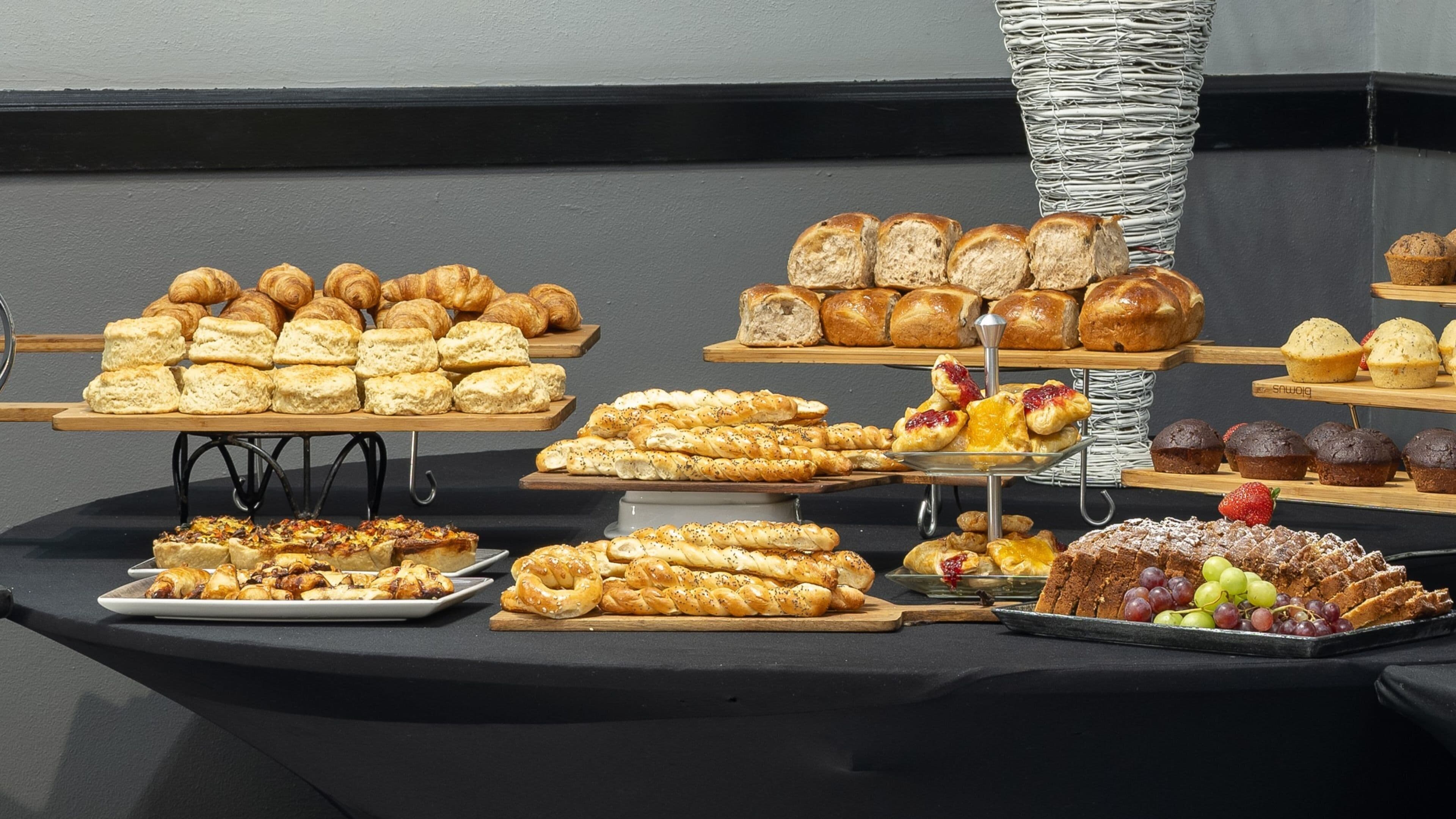 A buffet table with various baked goods including pastries, bread, and desserts.