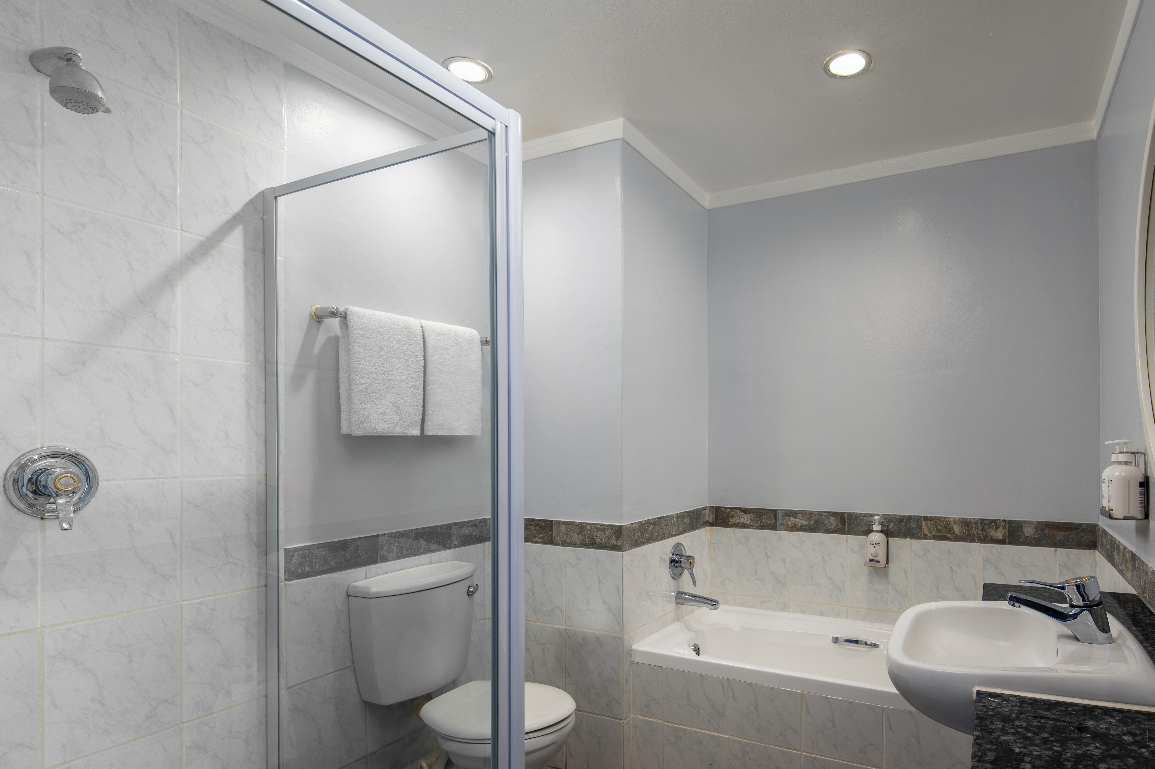 Une salle de bain moderne dotée d’une douche à parois de verre, de toilettes, d’une baignoire et d’un lavabo.