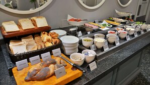 A buffet with various breads, pastries, and cold dishes. - Holiday Inn Johannesburg Airport by IHG (Boksburg)