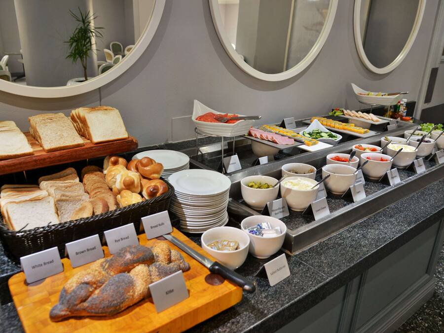 A buffet with various breads, pastries, and cold dishes.