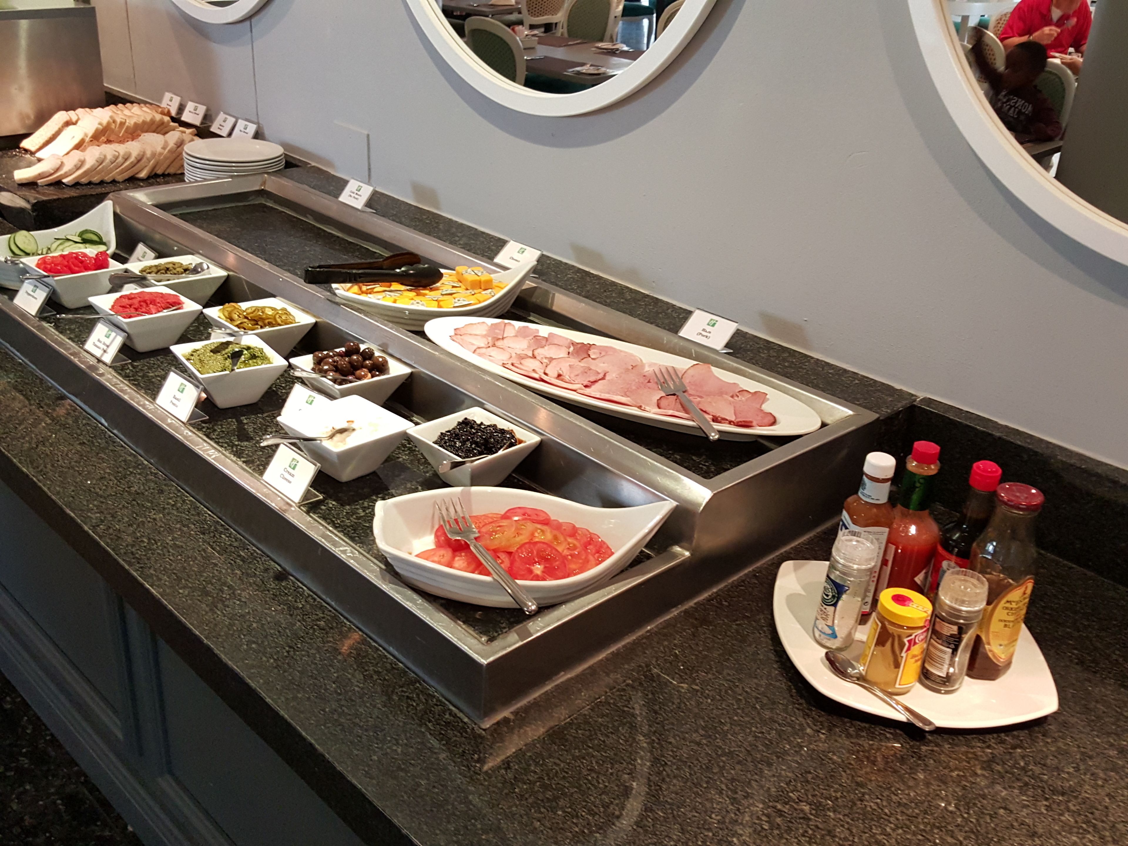 A buffet with various food items and condiments.