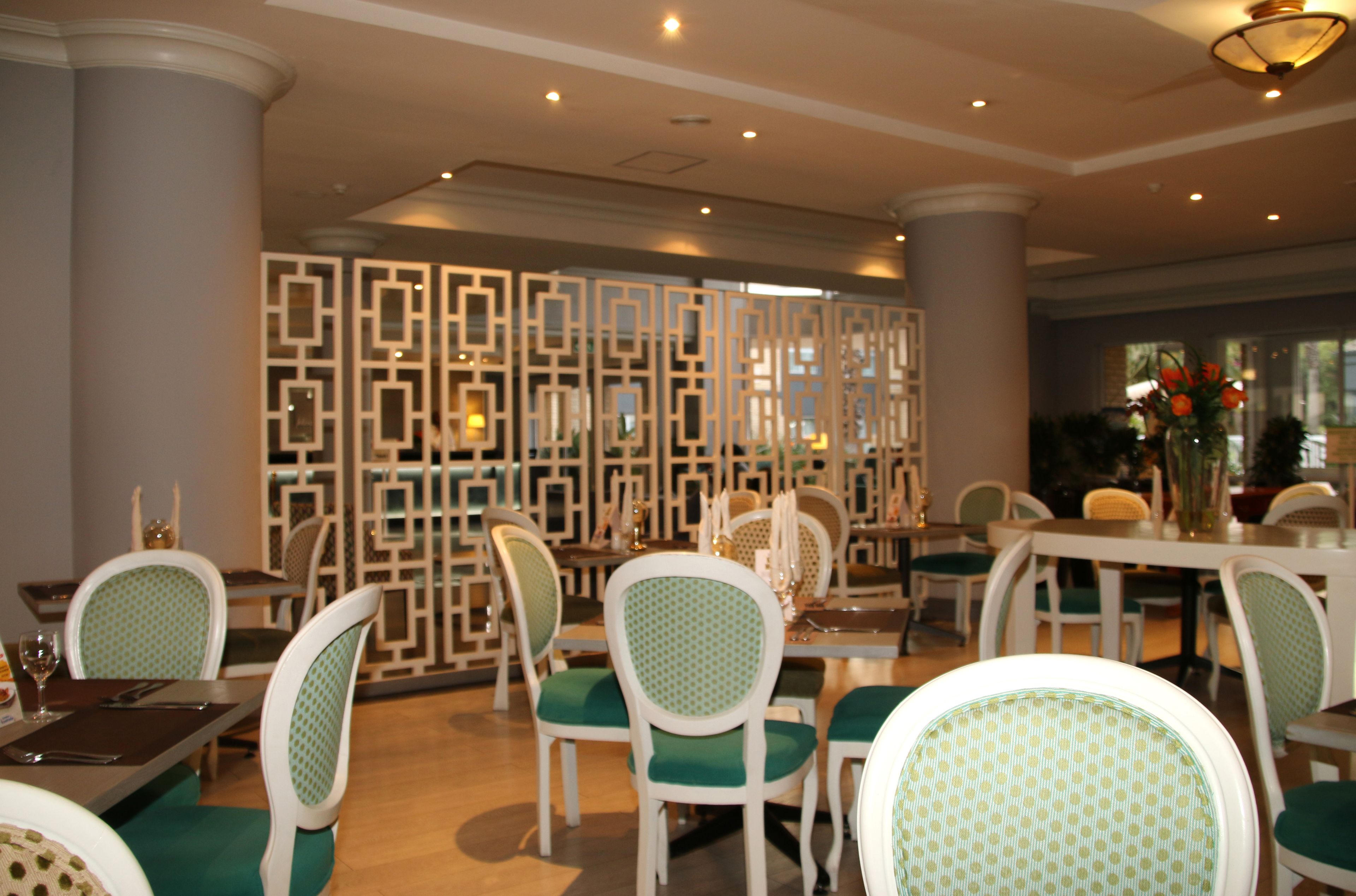 A dining area with white and green chairs, a decorative partition, and a table set for a meal.