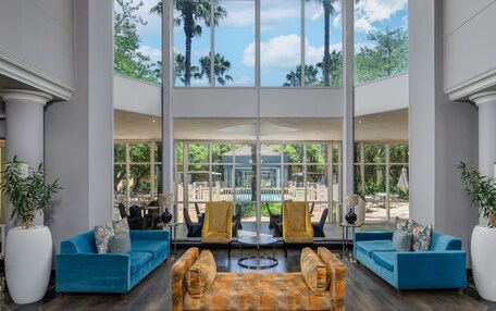 A spacious lobby with large windows, blue sofas, and a central coffee table.