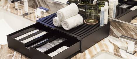 A bathroom counter with a marble sink, a black tray holding toiletries, and a mirror above.