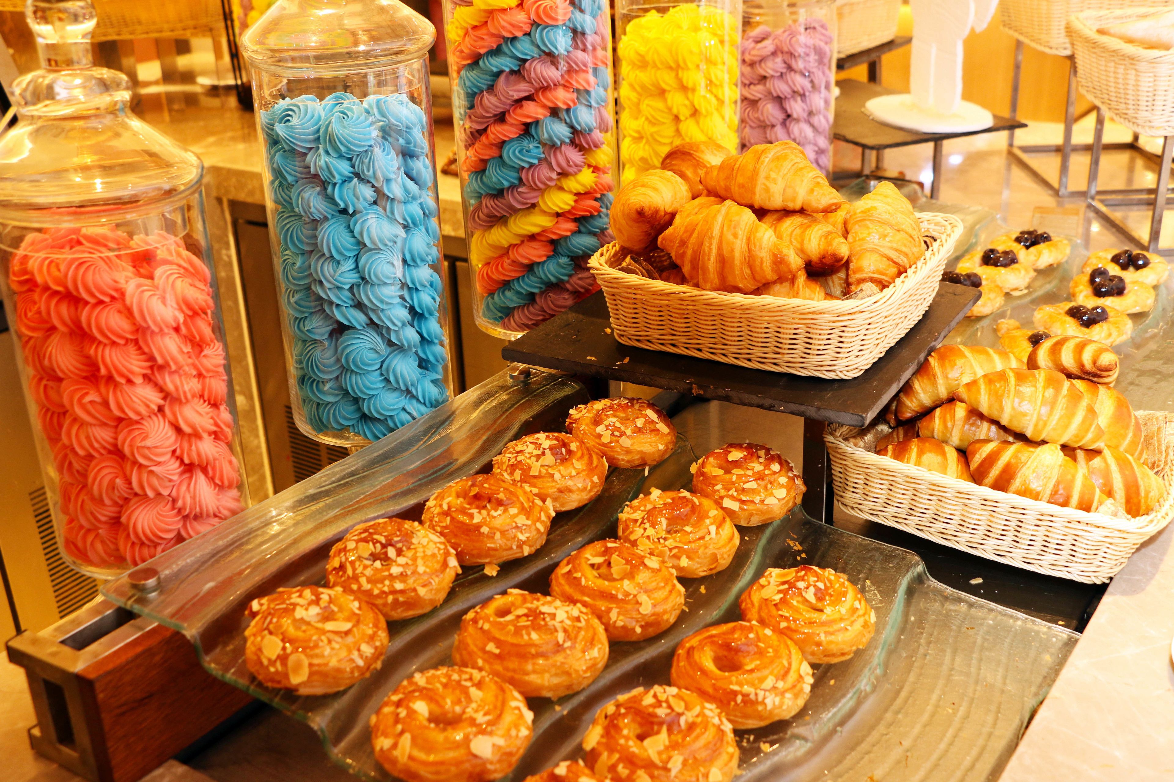 Una bandeja con pasteles y postres, incluyendo croissants y pasteles cubiertos de glaseado de colores.