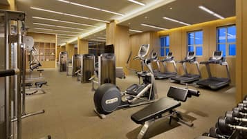 Un gimnasio moderno con diversos equipos de ejercicio, como cintas de correr, máquinas de pesas y una banca.