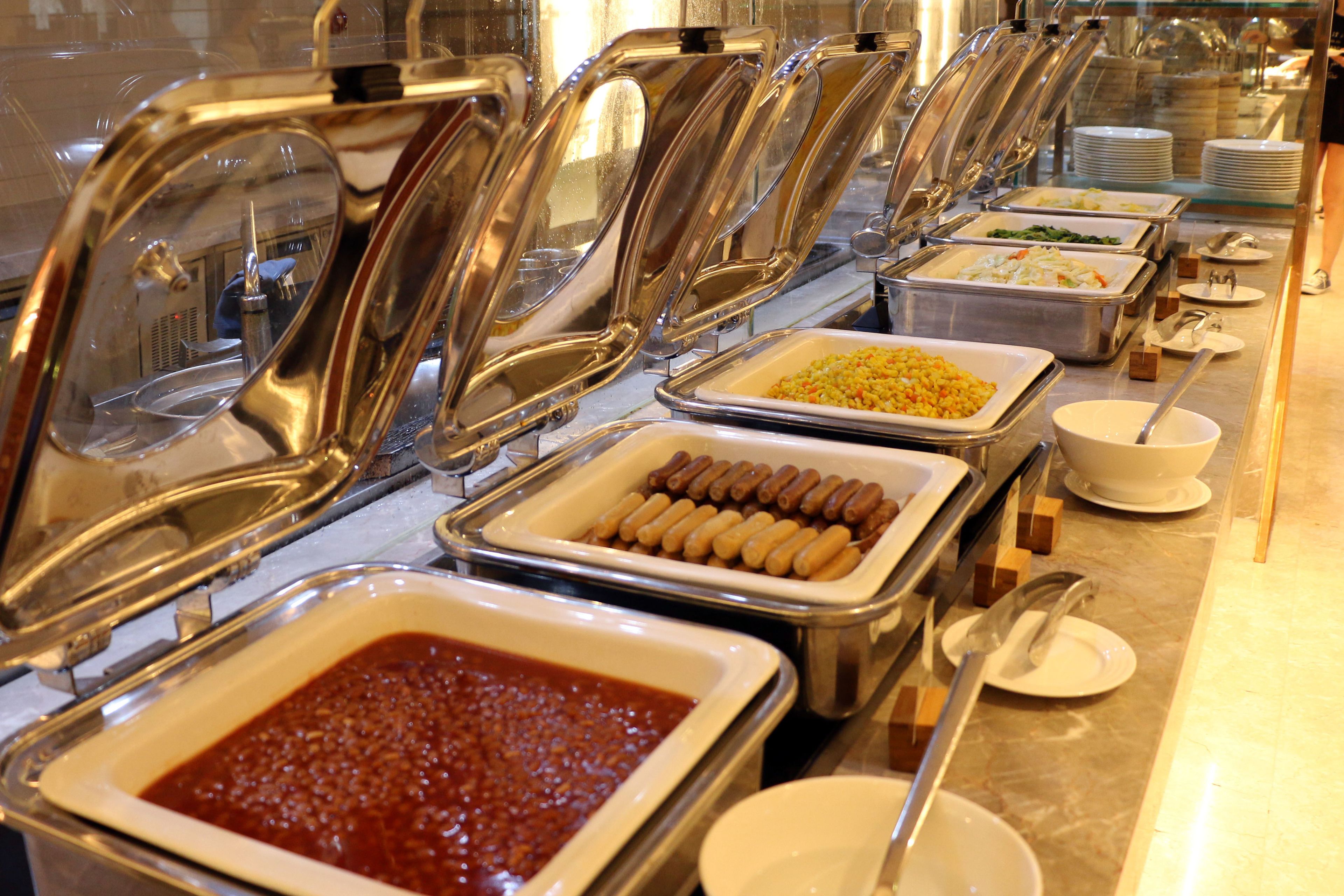 Ein Buffet mit verschiedenen Speisen, darunter eine große Schüssel Chili, Wannen mit Würstchen und weitere Gerichte.