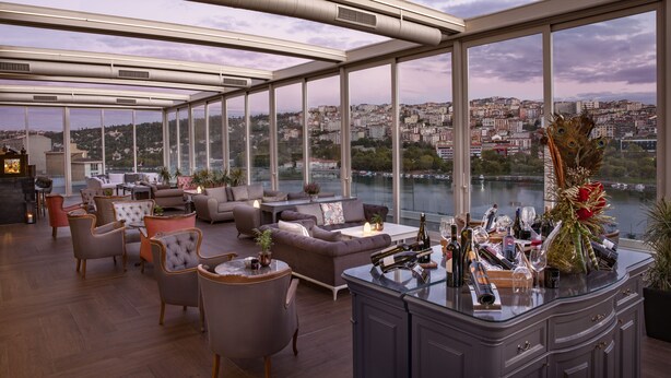 A spacious rooftop lounge with modern furniture, a bar area, and a panoramic city view. - Lazzoni Hotel (Istanbul)