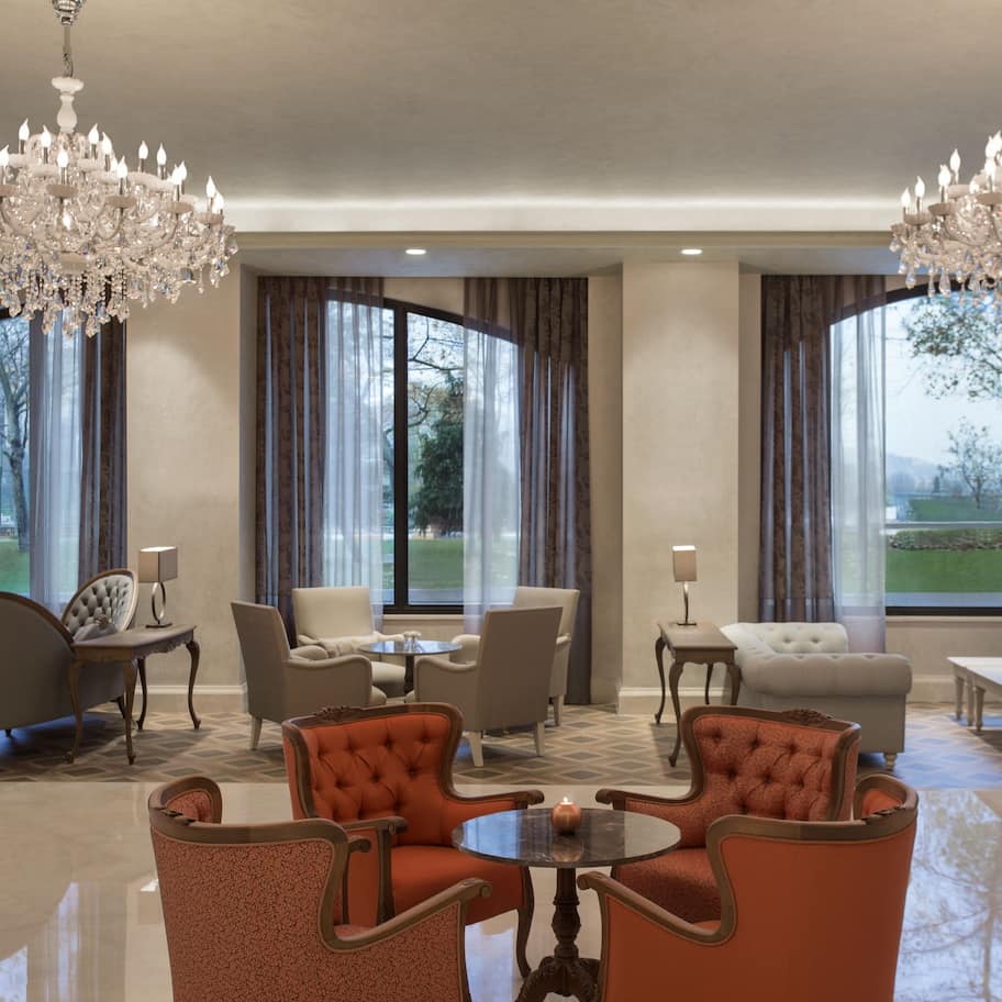A spacious living room with a chandelier, large windows, and a view of the outdoors.