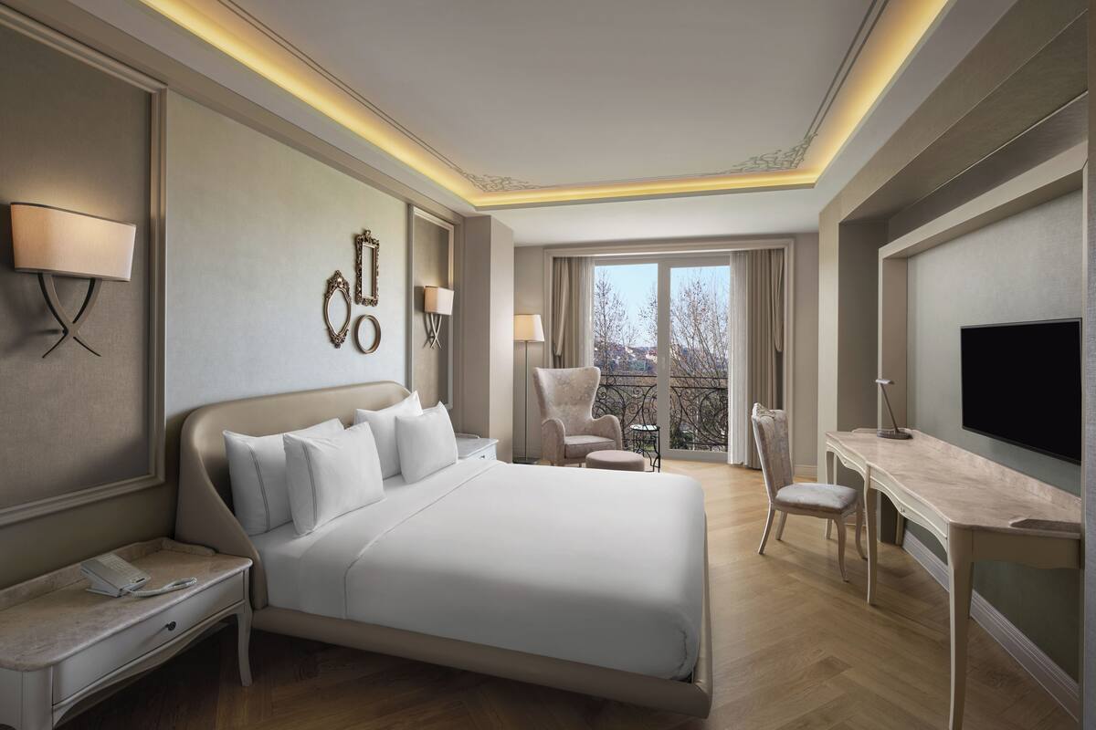 A hotel room with a bed, desk, chair, and a TV.