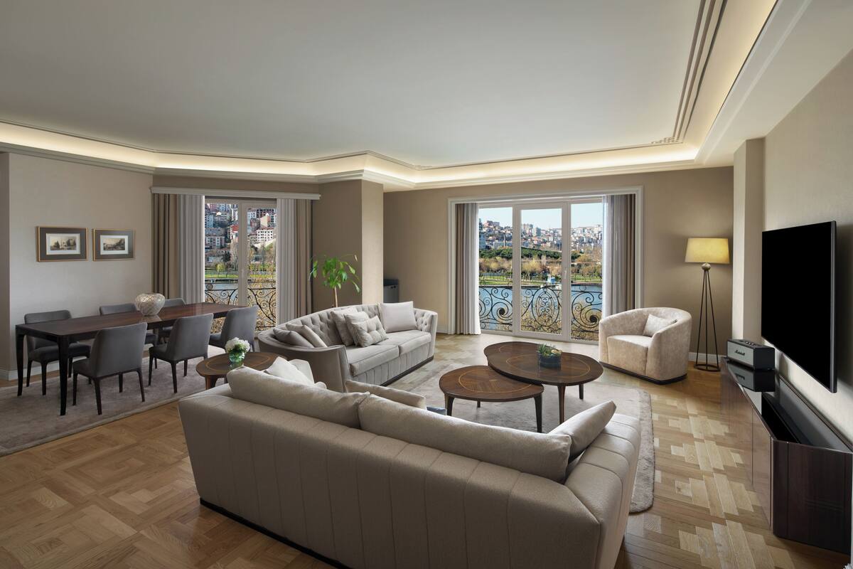 A modern living room with a sofa, coffee table, TV, and dining area.