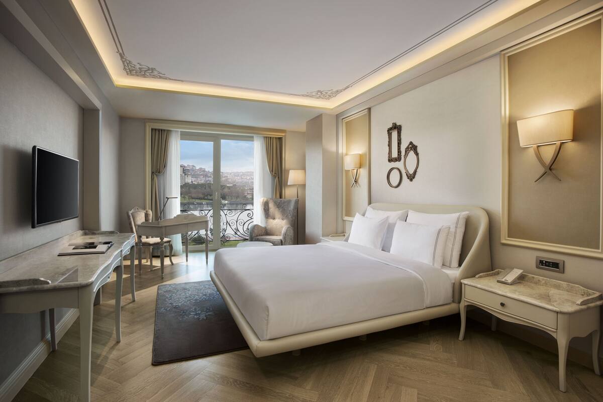 A hotel room with a bed, desk, chair, and a TV.