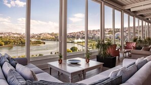 A spacious living area with large windows offering a view of a river and cityscape. - Lazzoni Hotel (Istanbul)