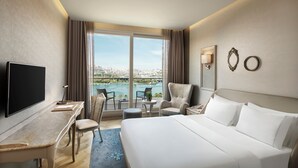 Une chambre d’hôtel équipée d’un lit, d’un bureau, d’une télévision, d’une chaise et offrant une vue sur un plan d’eau.